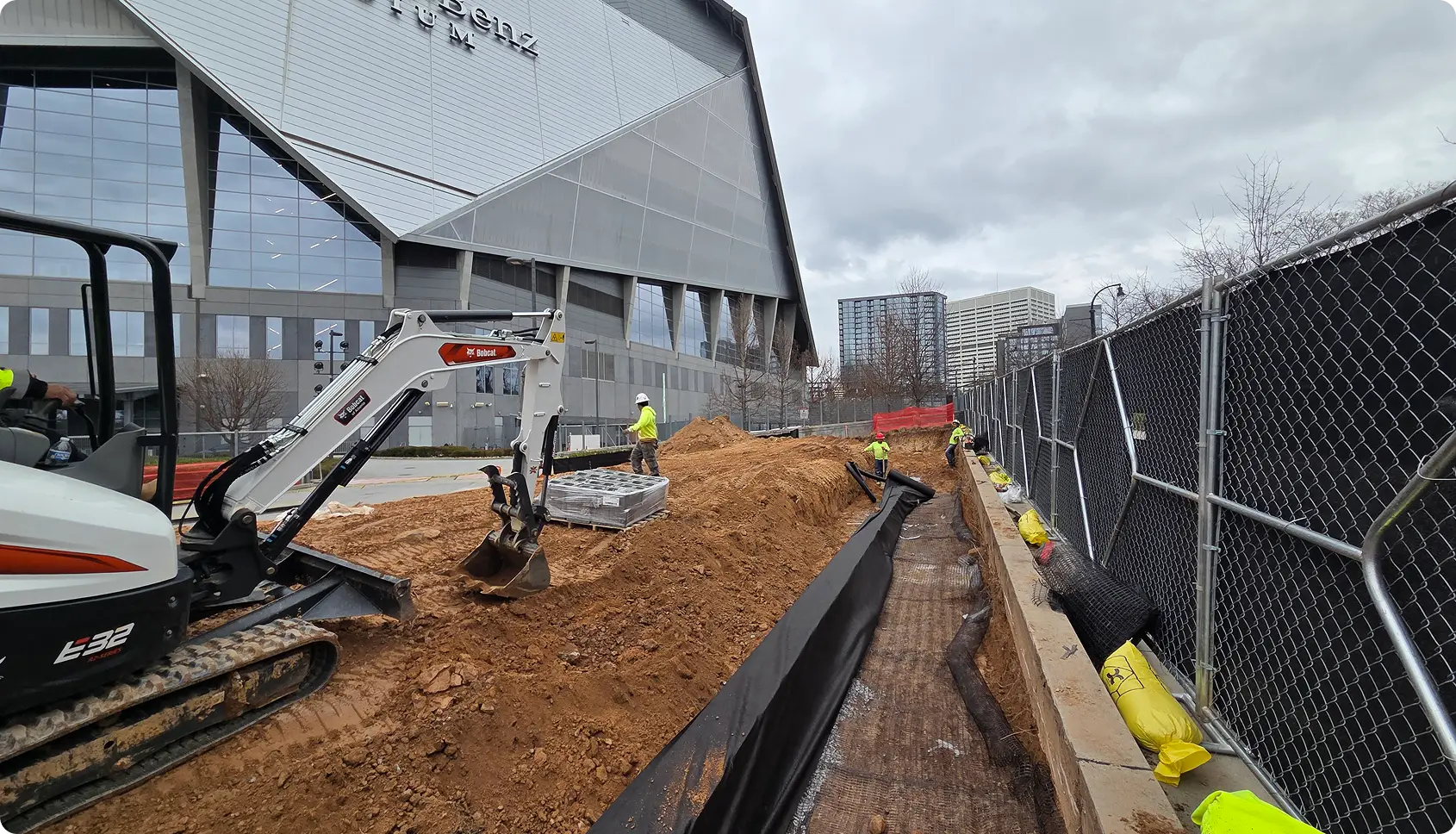 Construction site with excavator and workers outside building.